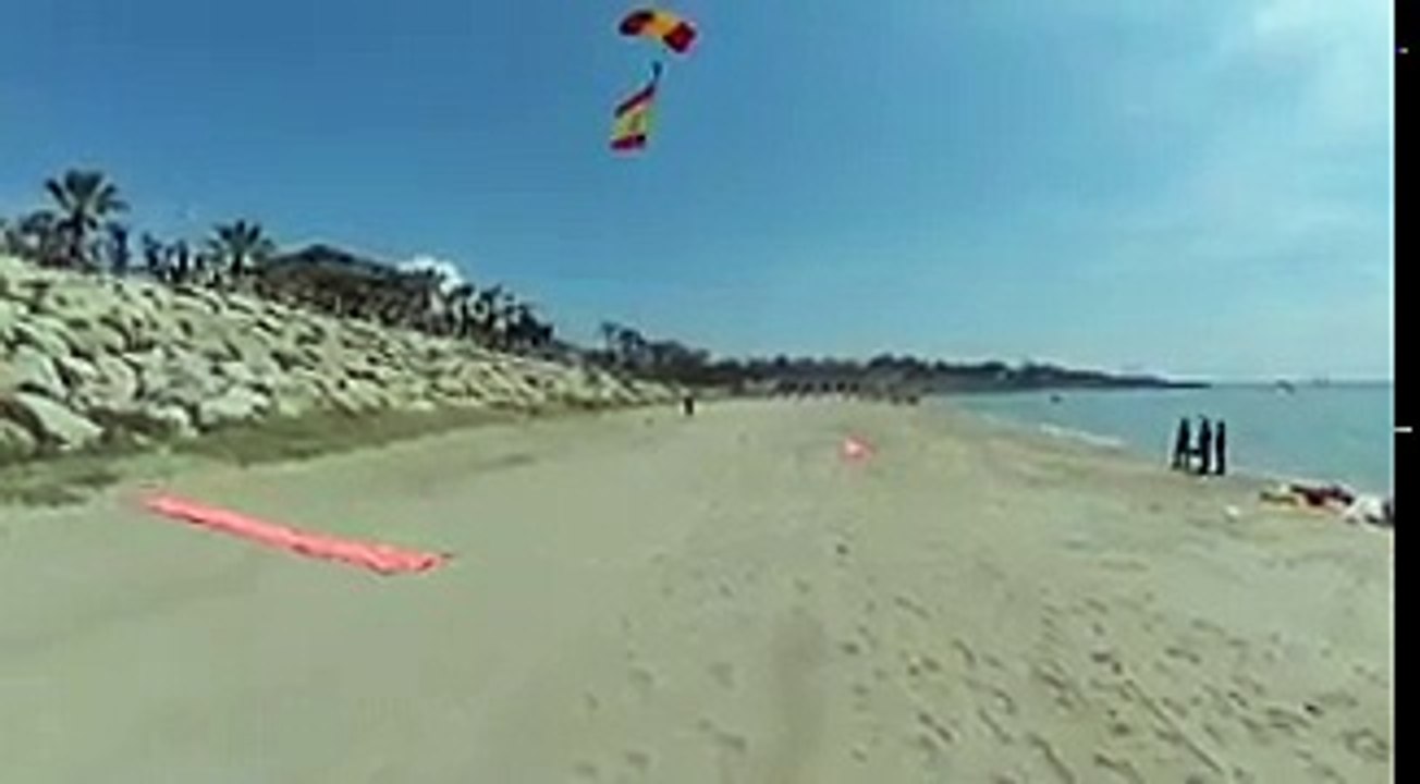 Aplausos en la "Playa del Milagro", Tarragona, cuando aterriza un paracaidista con la bandera de España