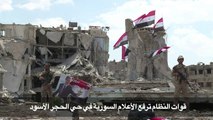 قوات النظام ترفع العلم السوري في حي الحجر الاسود