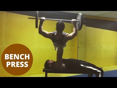Fitness fanatic lifts friend in a bench press of over 120kg.