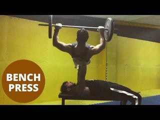 Fitness fanatic lifts friend in a bench press of over 120kg.
