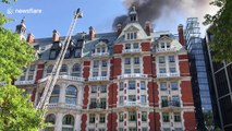 Firefighter inspects Mandarin Oriental hotel fire while on top of tall ladder