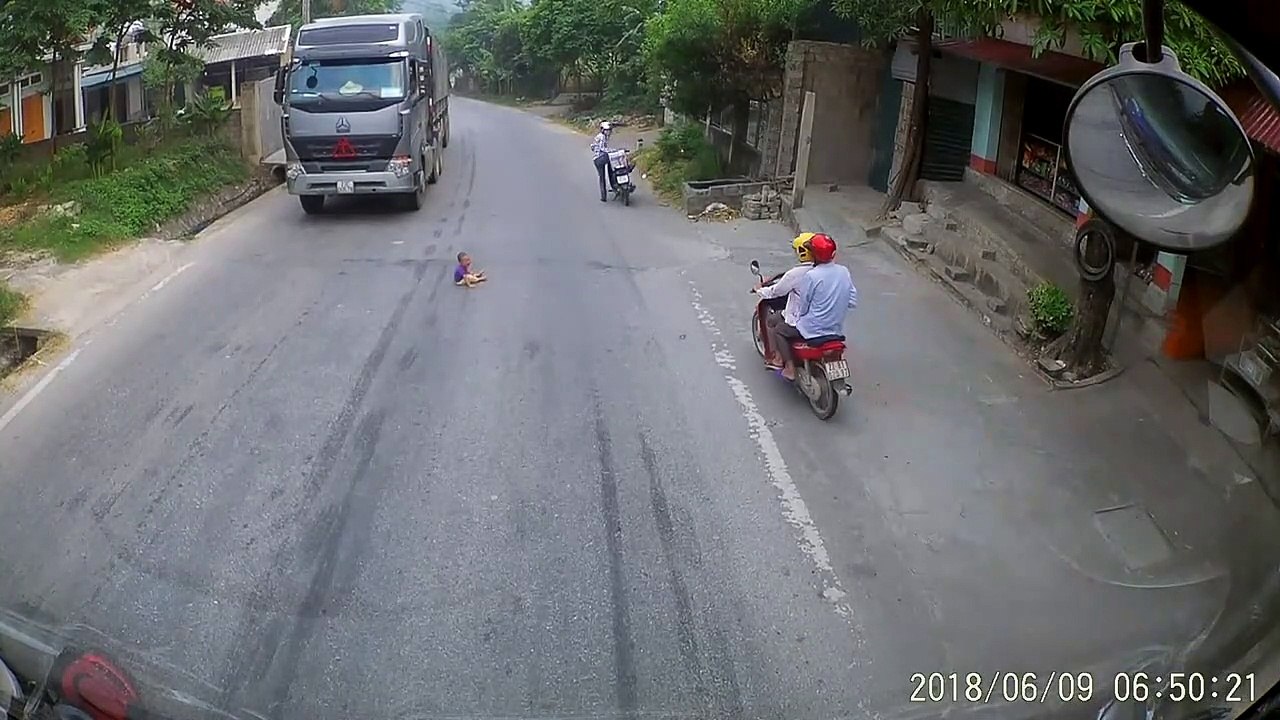 Un bébé traverse la route tout seul au moment ou 2 camions approchent