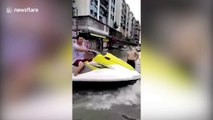 Man jet skis across flooded road in China