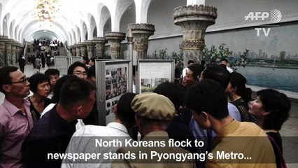 North Koreans look at pictures of Kim with Trump