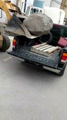 Régis charge un rocher dans un pick-up