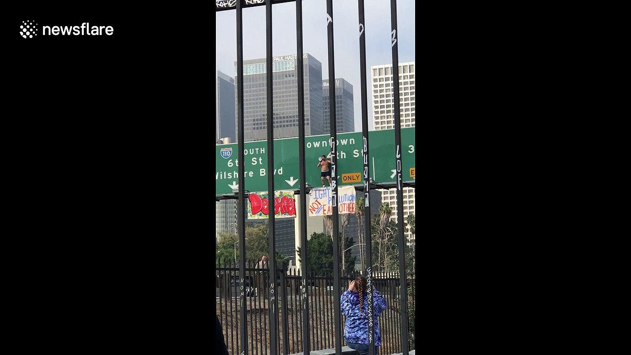 Man on freeway sign brings traffic to a standstill in downtown Los Angeles