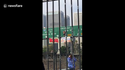 Man on freeway sign brings traffic to a standstill in downtown Los Angeles