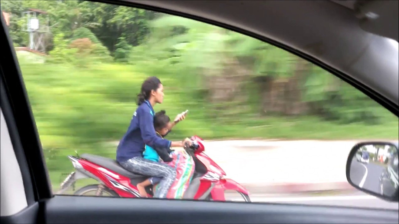 Cette femme en mobylette envoie un texto à deux mains avec son fils assis devant elle