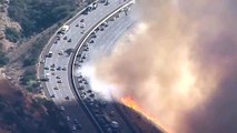 Californie  un hélicoptère largue de leau sur une autoroute au bord des flammes