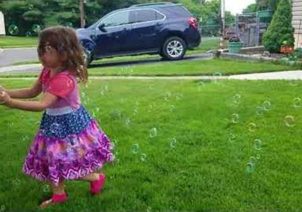 Little Girl Has Fun Chasing Bubbles