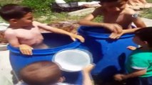 Ağrı’da sıcaktan bunalan çocuklar su dolu varillerde serinliyor