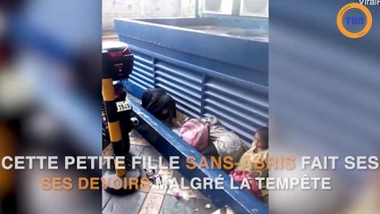 Petite fille sans abris qui fait ses devoirs sous la pluie