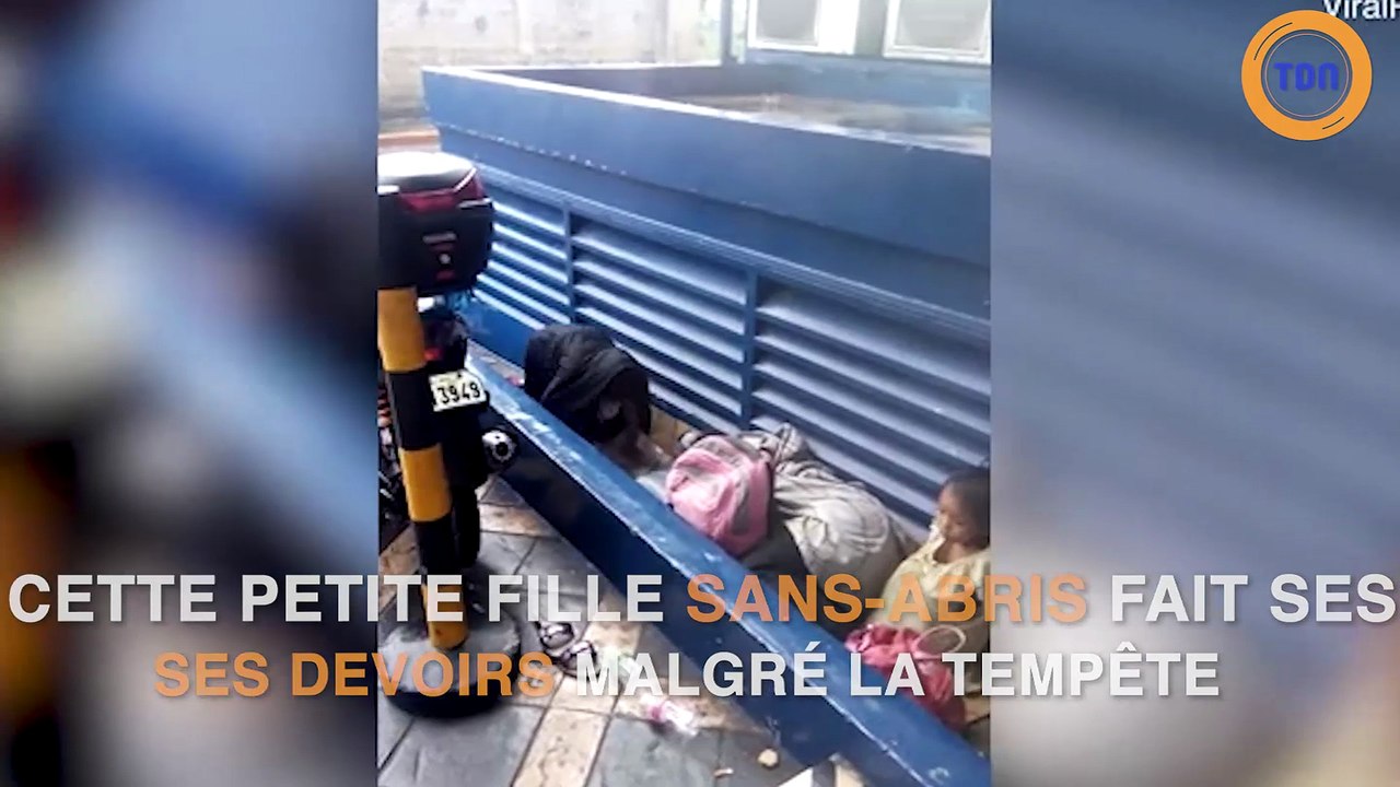 Petite fille sans abris qui fait ses devoirs sous la pluie