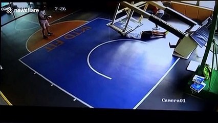 Guy gets slammed by basketball stand when it falls on top of him