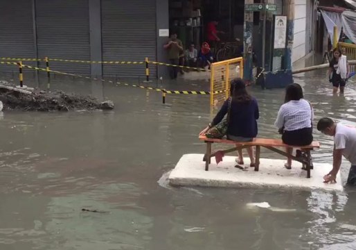 Manila Residents Ride on Makeshift Rafts in Flooded Street