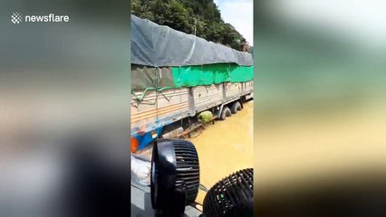 Trucks struggle through road after typhoon causes flooding in Vietnam
