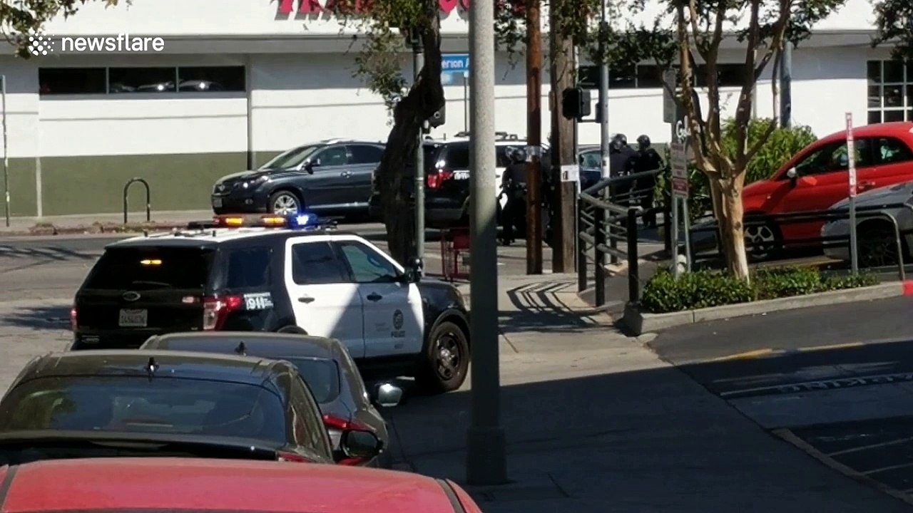 Police officers take cover behind SUV during hostage standoff in Los Angeles