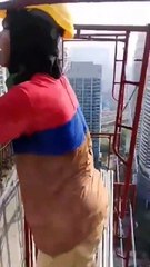 Des ouvriers montent un échafaudage au sommet d’un immeuble sans aucune sécurité