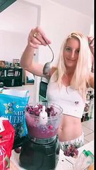 Une jeune femme essaie de mettre une cuillère dans un blender en marche