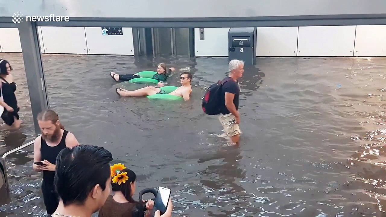 Commuters wade and float through flooded Swedish station