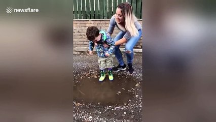 Boy with Cerebral palsy, laughs with joy as he splashes in puddle for the first time