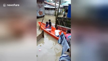Children use boat to get around village during flooding in the Philippines