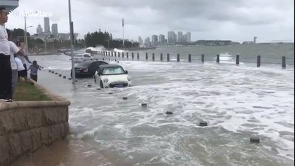 Drivers battle to stop cars from floating away as typhoon hits
