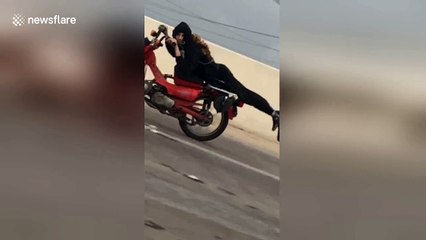 Daredevil speeds down highway on motorbike clutching just his handlebars