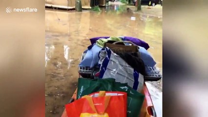 Man pushes belongings on kayak in flooded France campsite