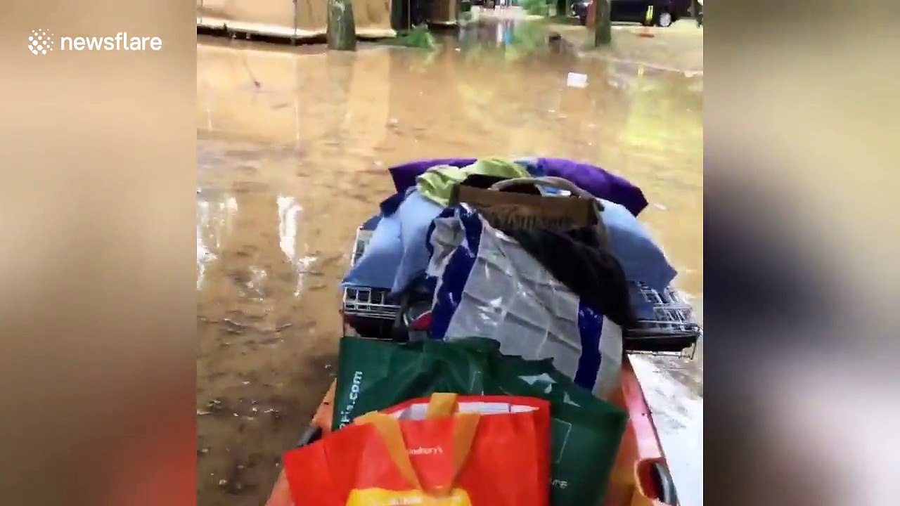 Man pushes belongings on kayak in flooded France campsite