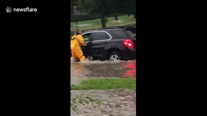 Firefighter rescues driver as fast-moving floodwaters carry vehicle away