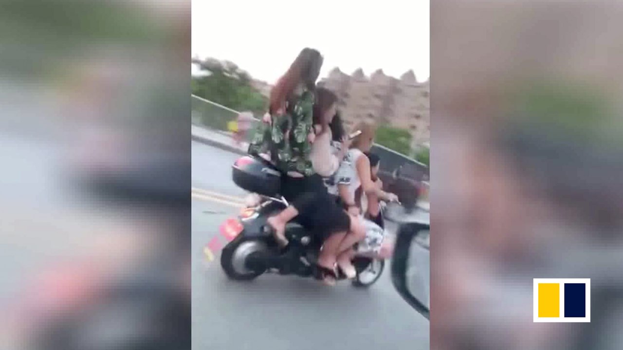 Five Chinese women ride on one scooter on busy road
