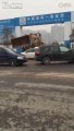 Une pelleteuse pousse des voitures garées à l'entrée d'un chantier