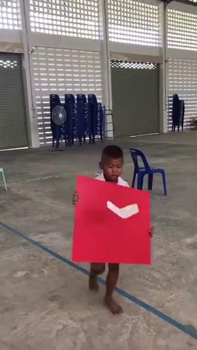 Cet enfant fait voler un avion en papier à l'aide d'un carton