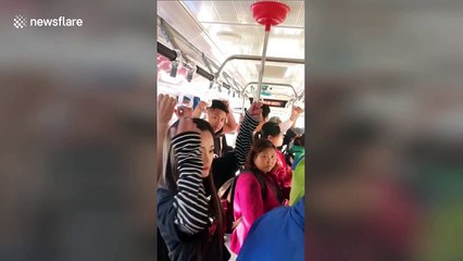 Chinese woman uses plunger as a makeshift handle on bus
