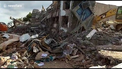 Excavator digs through debris from fallen hotel on earthquake-stricken Indonesia island