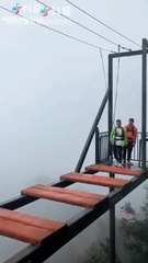 Un chinois traverse une passerelle dangereuse alors qu'il est mal attaché