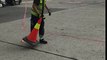 Airport worker flips a cone onto another traffic cone