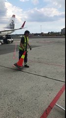 Airport worker flips a cone onto another traffic cone