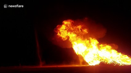 Dust devils swirl next to raging bonfire