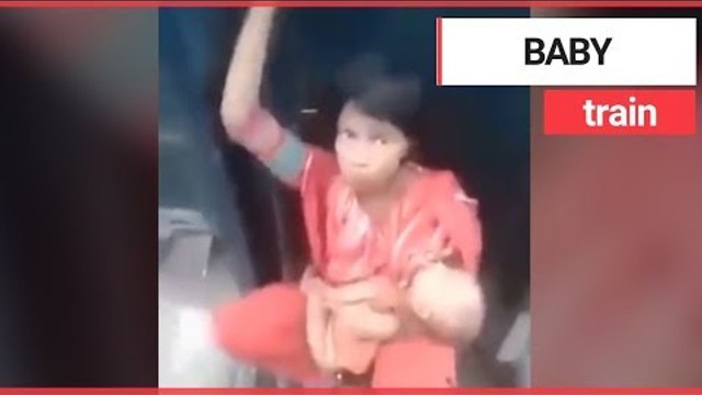 Mum cradles baby while sat between two speeding train carriages | SWNS TV