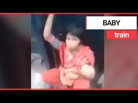Mum cradles baby while sat between two speeding train carriages | SWNS TV