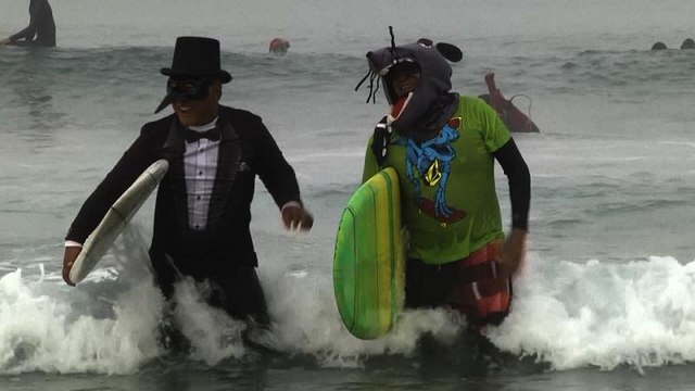 Surfistas disfrazados festejan Halloween sobre las olas en Newport Beach