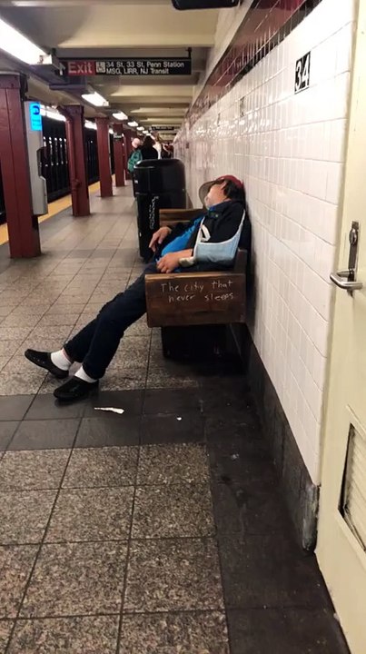 Un homme vêtu d'une veste bleue dort sur un banc