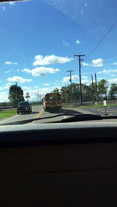 Un bus scolaire traverse un passage à niveau alors que les barrières sont fermées