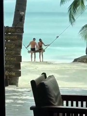 Un couple font de la balancoire sur une plage de rêve