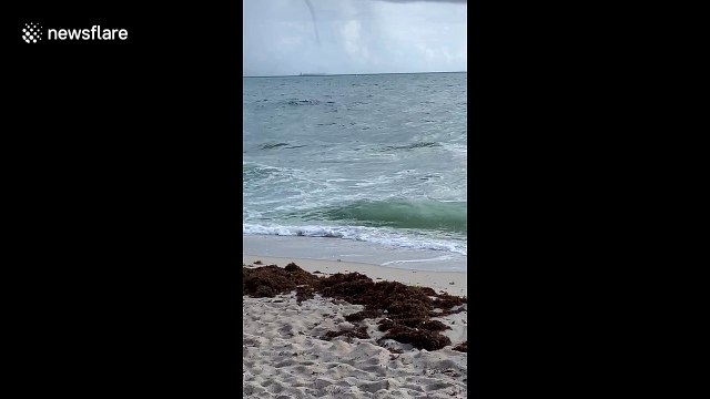 Water spout looms low over cargo ship