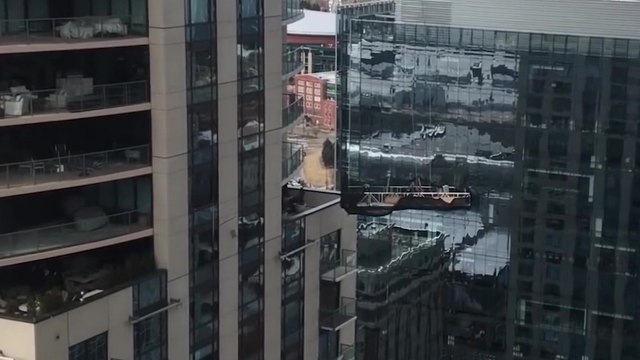 Des laveurs de vitres sur une nacelle se font malmener par le vent et s'encastrent dans une fenêtre