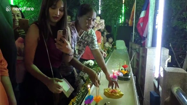 Worshippers send candle-lit baskets down a flume for Loy Krathong festival in Thailand