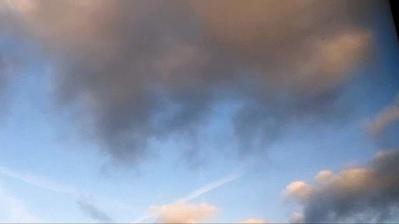 The Sky with Sunlit Clouds of a Creamy Pastel Pink Colour over a Blue Sky with Dark Clouds Entering